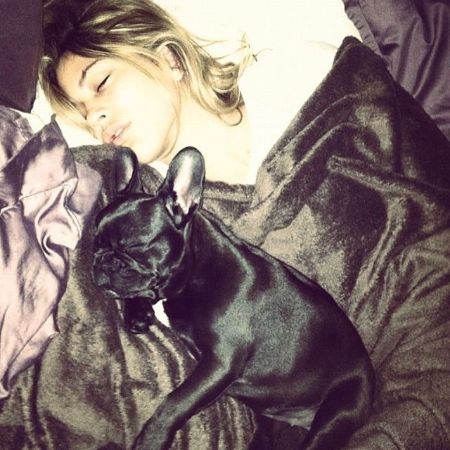 Kenya Kinski-Jones laying on her bed with her black  French Bull Dog, Banksy. 